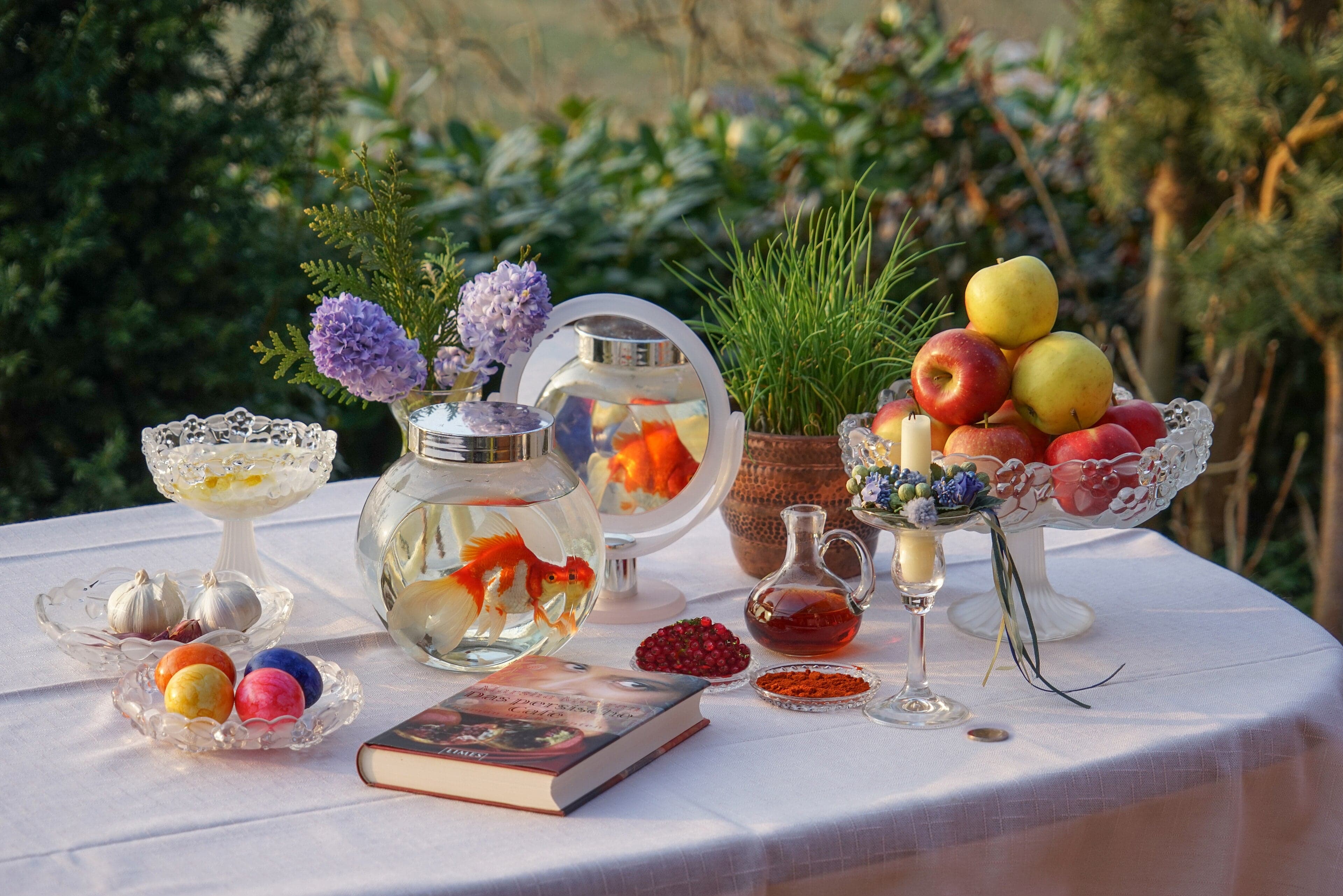 A beautiful haft-sin table set with sprouting green wheat, coloured eggs, apples, a goldfish bowl and other symbolic items