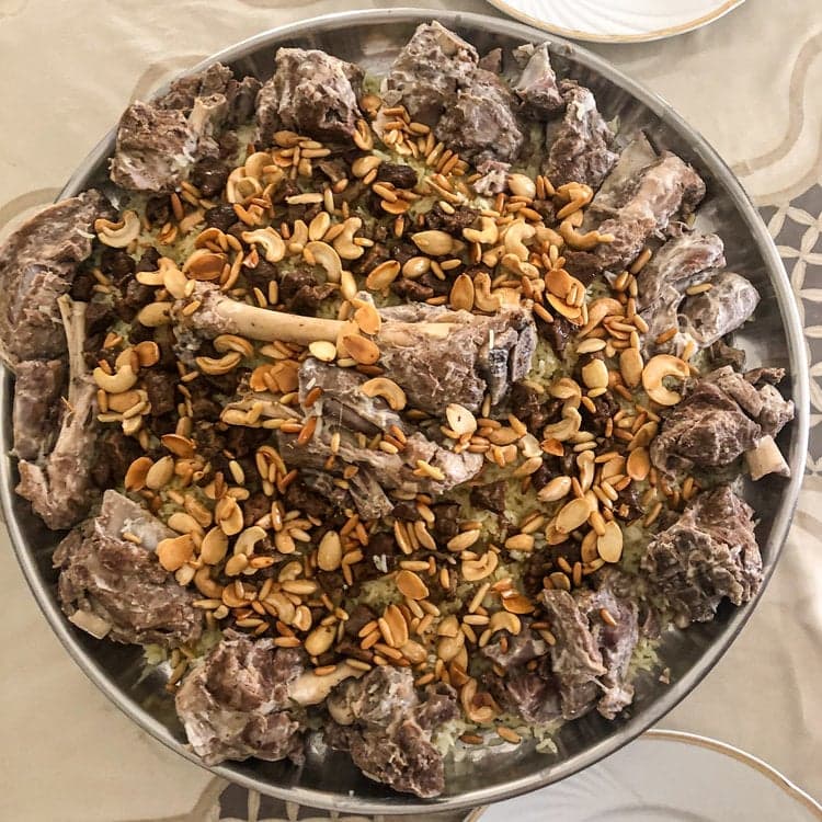 A large platter of mansaf with rice, lamb and jameed yogurt sauce piled high for a celebration