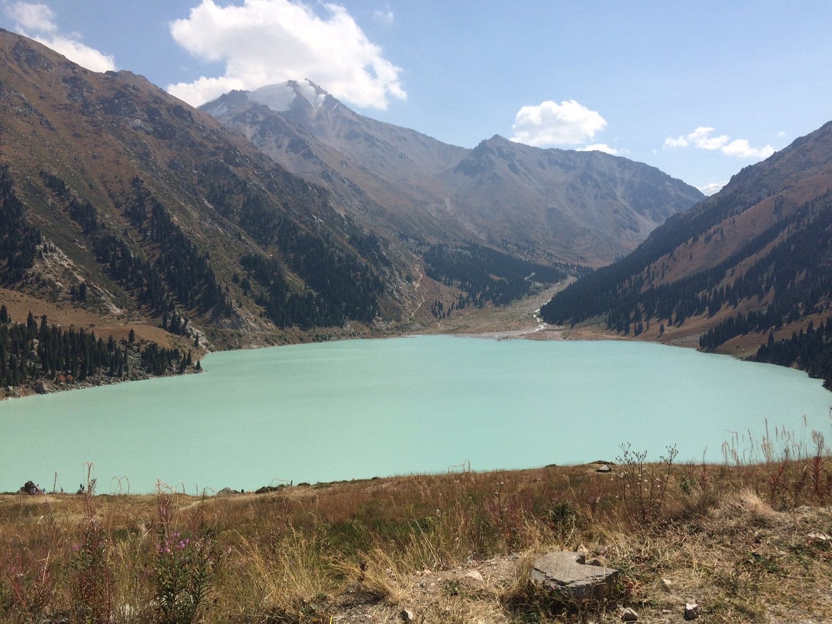 Bright turquoise Big Almaty Lake surrounded by snow-capped Tien Shan peaks