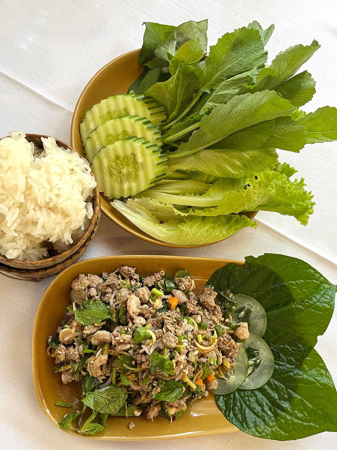 A bowl of fresh vegetable laap with herbs, chopped vegetables and toasted rice flakes