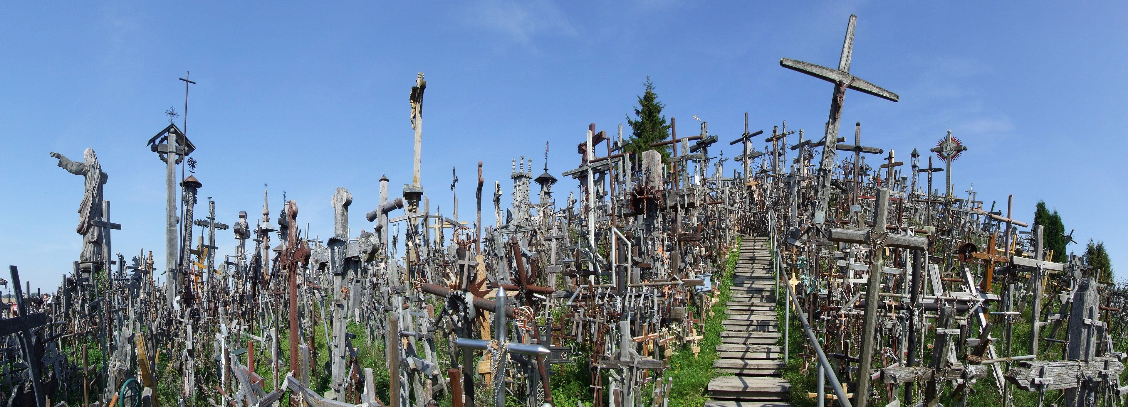 A hill completely covered in crosses of all sizes at sunrise, with mist in the background