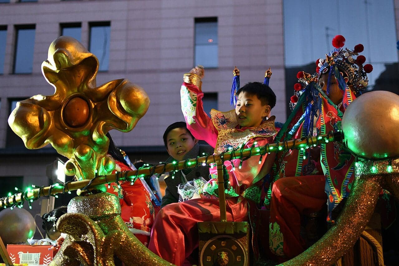 A glowing illuminated dragon float surrounded by fireworks during Macau's Chinese New Year night parade