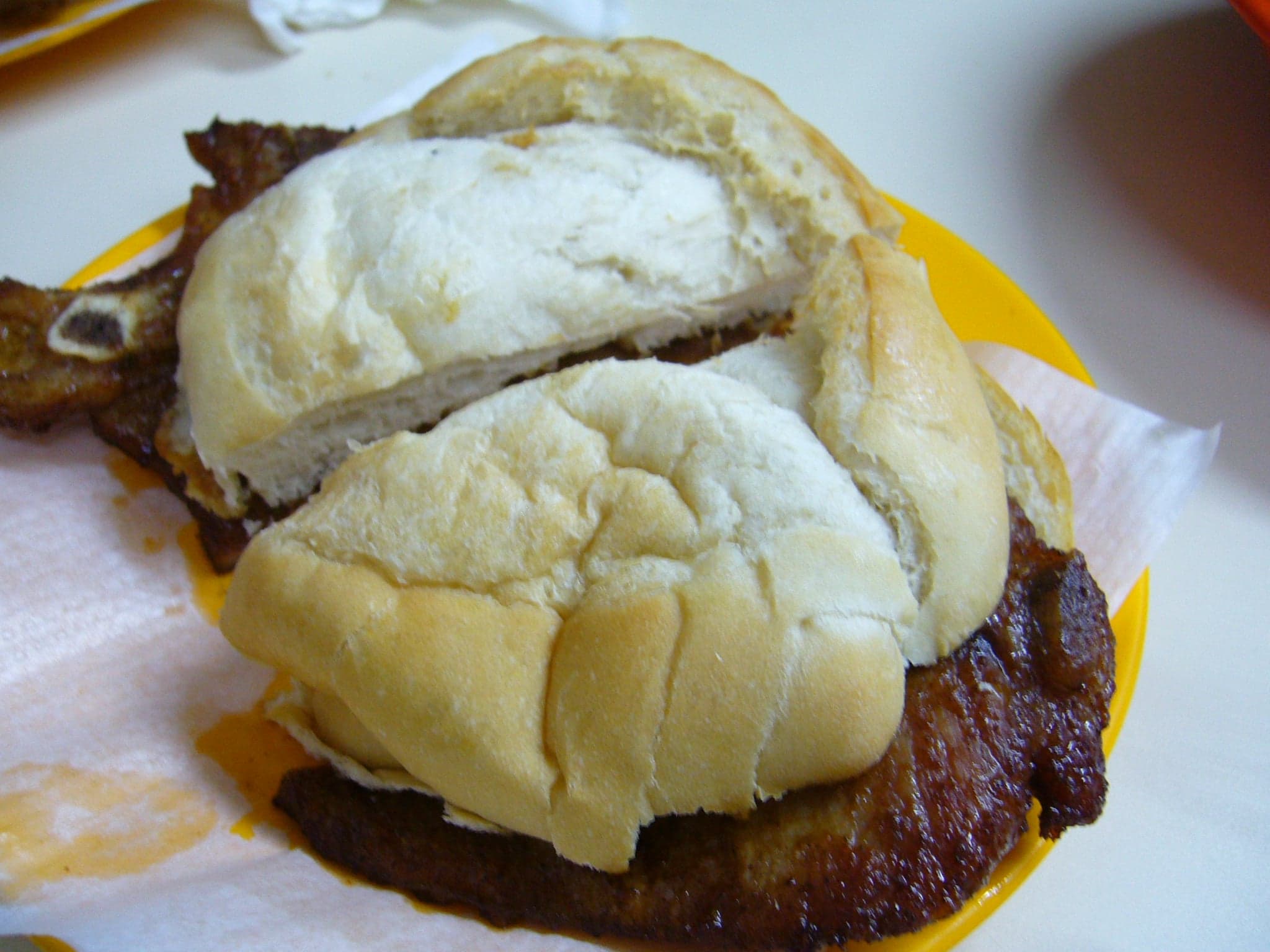 A crispy pork chop inside a white Portuguese bread roll - a Macau pork-chop bun