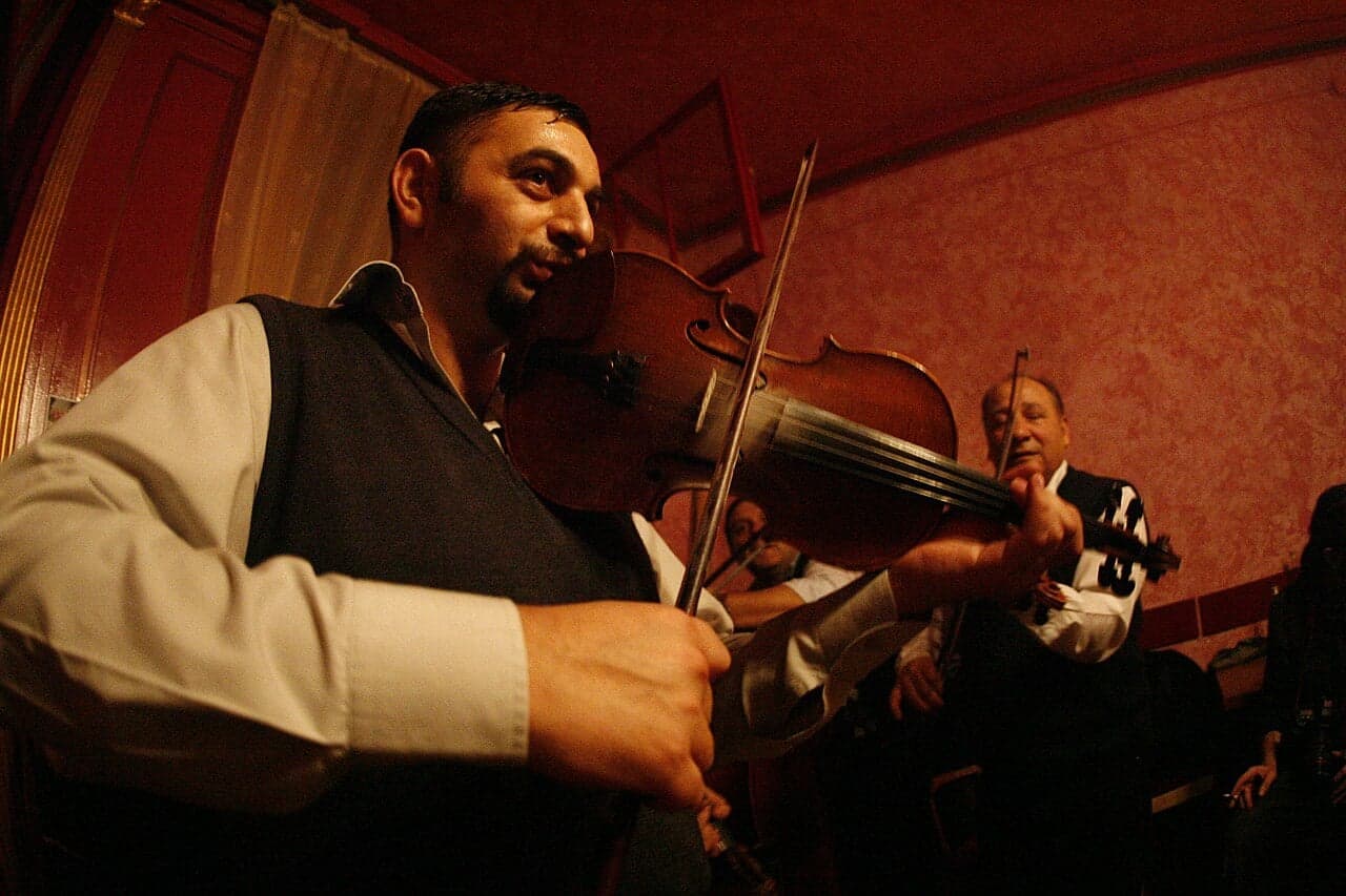 A Moldovan musician singing a doina in traditional costume in an outdoor setting