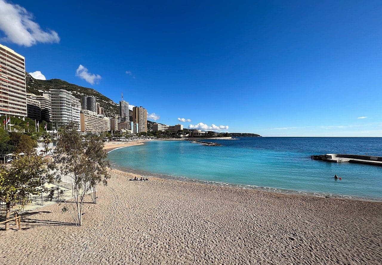 Larvotto Beach with calm blue Mediterranean water and the Monaco skyline behind