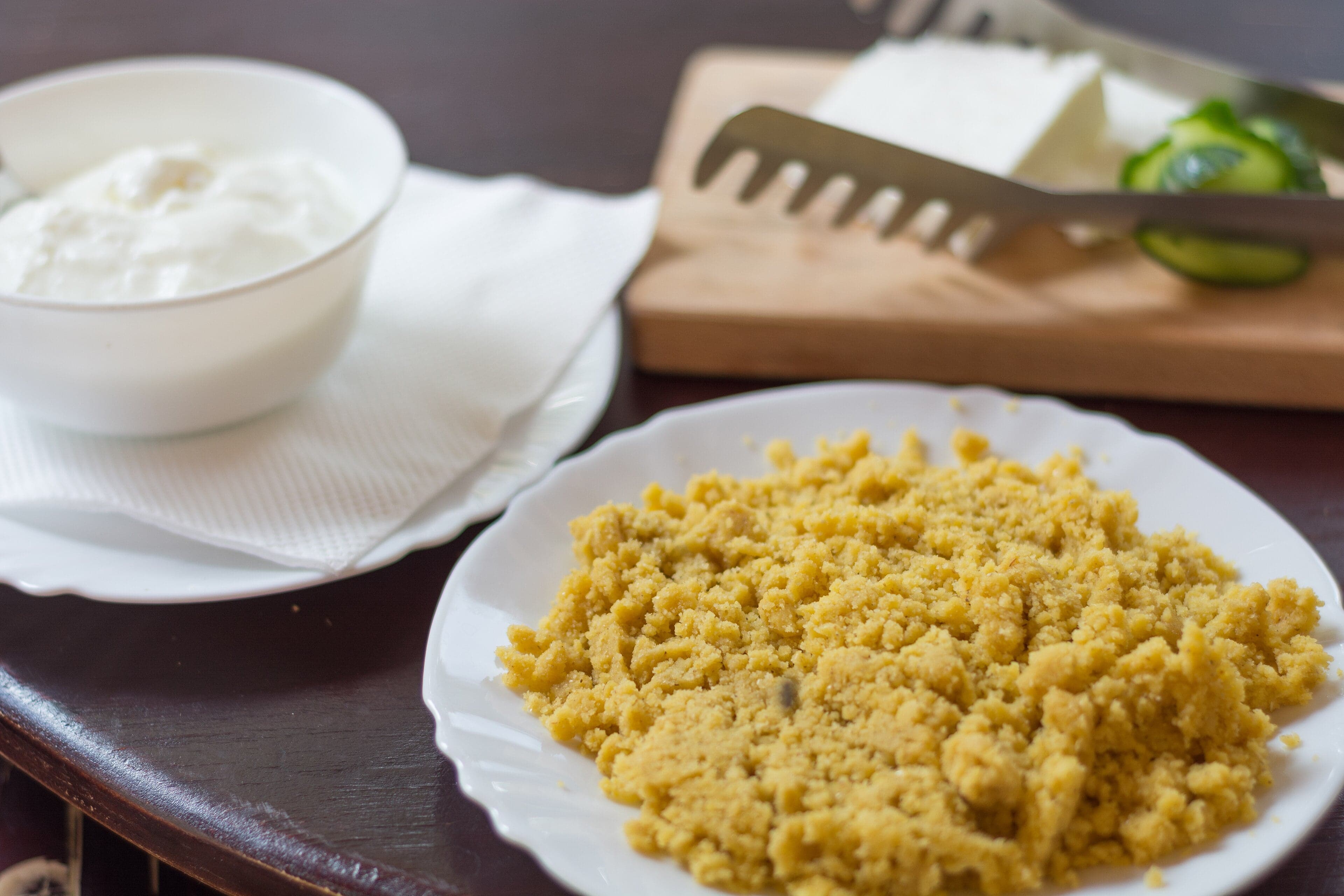 A bowl of thick golden kačamak topped with white kajmak cream and glistening butter