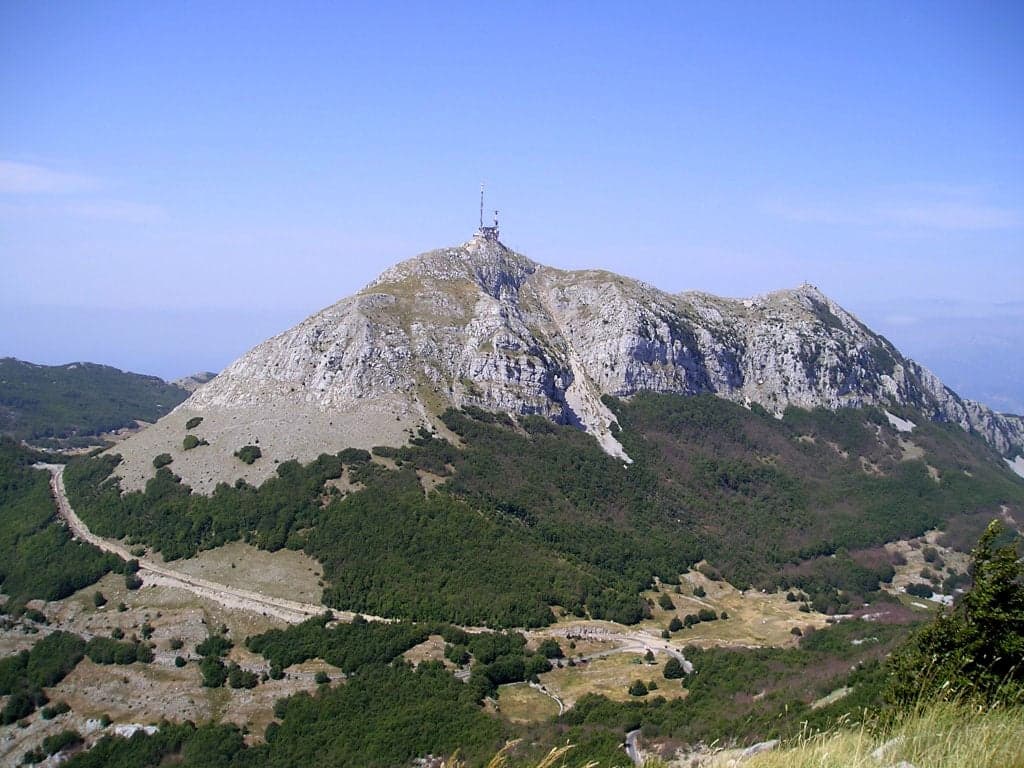 Green forested slopes of Lovćen Mountain with the Bay of Kotor glittering in the distance