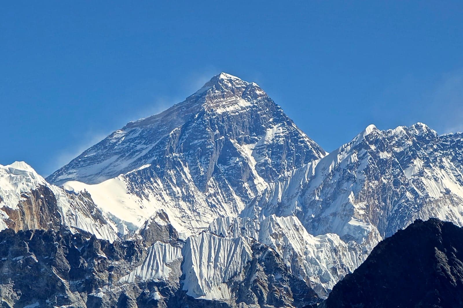 Mount Everest rising above the Himalayas under a blue sky