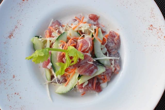 A bowl of ota ika - white fish pieces in creamy coconut sauce with lime and vegetables