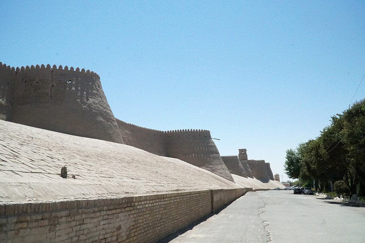The mud-brick walls and turquoise minaret of Khiva's old town under a blue sky