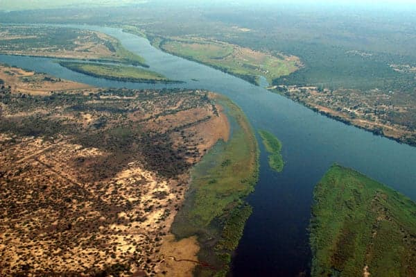 A wide stretch of the Zambezi River at sunset with a fishing boat